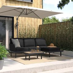 a black couch sitting on top of a patio under an umbrella