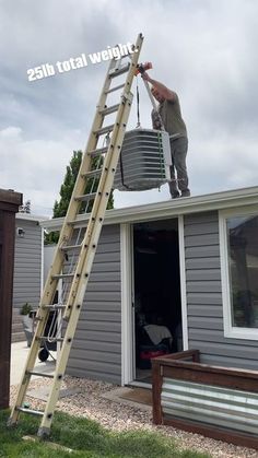 a man standing on top of a ladder next to a bucket filled with something in front of a house