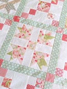 a quilted table topper with pink, green and white flowers on the edges