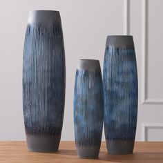 three blue vases sitting on top of a wooden table next to eachother