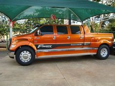 an orange pick up truck parked under a canopy