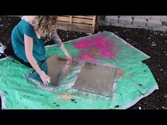 a woman is working on an art project in the garden with colored chalk and paint