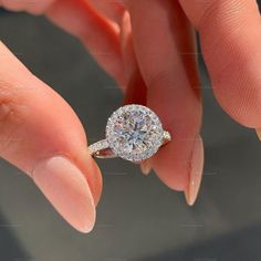 a woman's hand holding an engagement ring with a diamond center stone on it