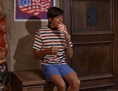 a young man eating a lollipop while sitting on a bench in front of a poster