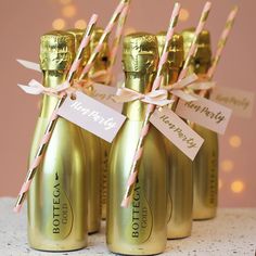 four champagne bottles with pink and gold straws tied to them, labeled happy birthday