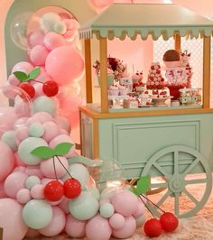 an ice cream cart with balloons and cherries on the top is set up for a party