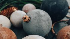 some balls are sitting on the ground with pine cones and other decorations around them,