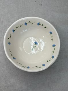 a white bowl with blue flowers painted on the side and green stems in the middle