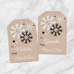 two tags with snowflakes on them sitting on top of a white marble surface