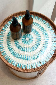 two bottles are sitting on top of a wicker tray with blue and white designs