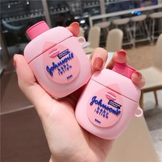 someone holding two pink baby bottles with blue writing on the top, and one has a pink lid