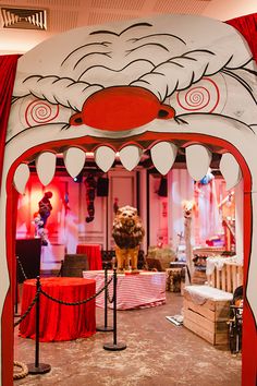 an entrance to a show with red curtains and decorations on the walls, including a lion's head