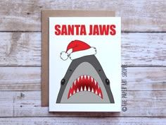 a christmas card with a santa hat on top of a shark's mouth and the words santa jaws