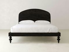 a black bed with white sheets and pillows on it's headboard is shown