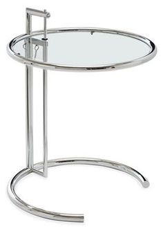 a round glass table with metal legs and a circular glass tray on the bottom that is holding a magazine rack