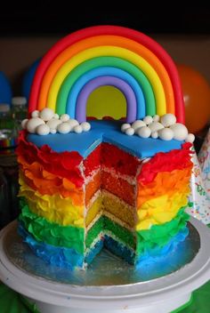 a rainbow cake on a plate with a slice taken out