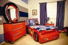 a bedroom decorated in red, blue and white with a race car theme on the bed