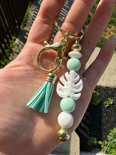 a hand holding a keychain with beads and a tassel