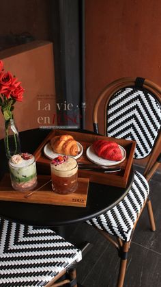 a table topped with two plates of food next to a vase filled with red flowers