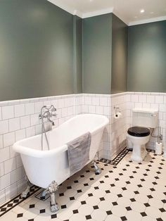 a white bathtub sitting next to a toilet in a bathroom under gray painted walls