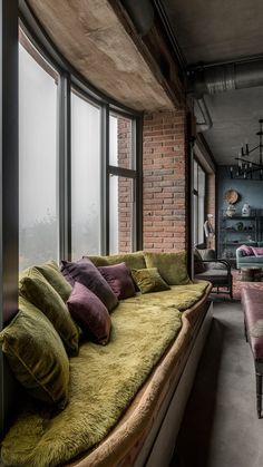 a large window with lots of pillows on it in front of a brick wall and floor