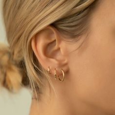 a close up of a person wearing gold earring with small hoops on their ears