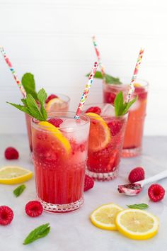 three glasses filled with raspberry lemonade and mint garnish on a table