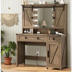 a wooden desk with a mirror and lights on top of it next to a potted plant