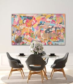 a dining room table with four chairs and a large painting on the wall above it