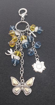 the butterfly charm is attached to a keychain with charms and beads on it