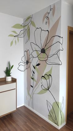 a wall with flowers painted on it and a plant in the corner next to it