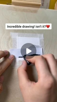 someone is drawing something on a piece of paper with black marker and some type of sticker