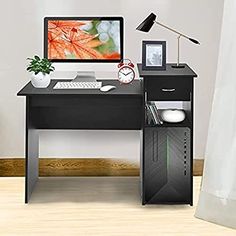 a computer desk with a monitor, keyboard and mouse next to a plant on it