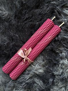 two pink crocheted umbrellas tied together on top of a gray rug with a bow