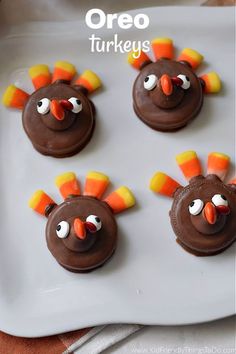 four chocolate turkeys on a white plate with orange and yellow candies in the middle