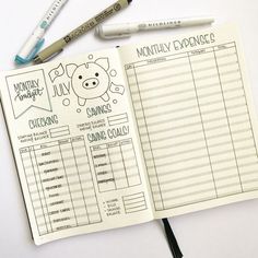 an open planner with pens and markers next to it