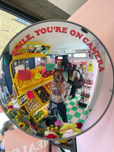 the reflection of a woman taking a selfie in a mirror at a market place