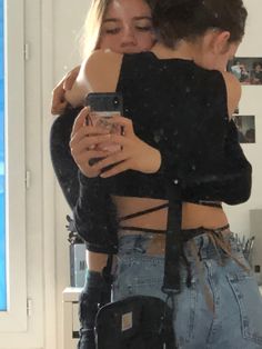 two young women hugging each other in front of a mirror