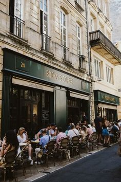 people sitting at tables in front of a store