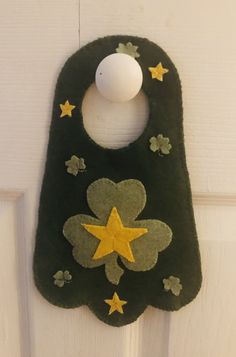 a green door hanger with yellow stars and a white ball on it's side