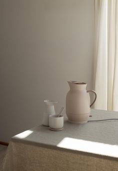 a white pitcher and two cups on a table