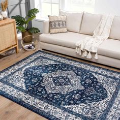 a living room with white furniture and blue rug