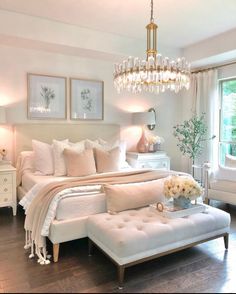 a bedroom with white furniture and chandelier hanging from the ceiling, along with pictures on the wall