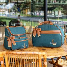 two blue bags sitting on top of a wooden table next to chairs and a window