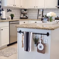 a kitchen with white cabinets and granite counter tops, hanging utensils on the wall