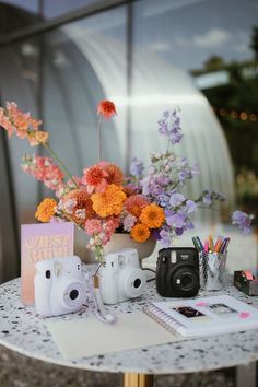 a table topped with flowers and cameras on top of it