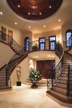 a large foyer with stairs and potted plants on the table in front of it