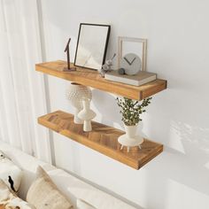 two wooden shelves with vases and plants on them in front of a white couch