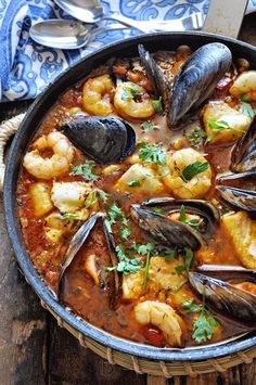 a pan filled with seafood and clams on top of a wooden table