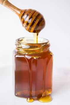 a wooden spoon pouring honey into a jar